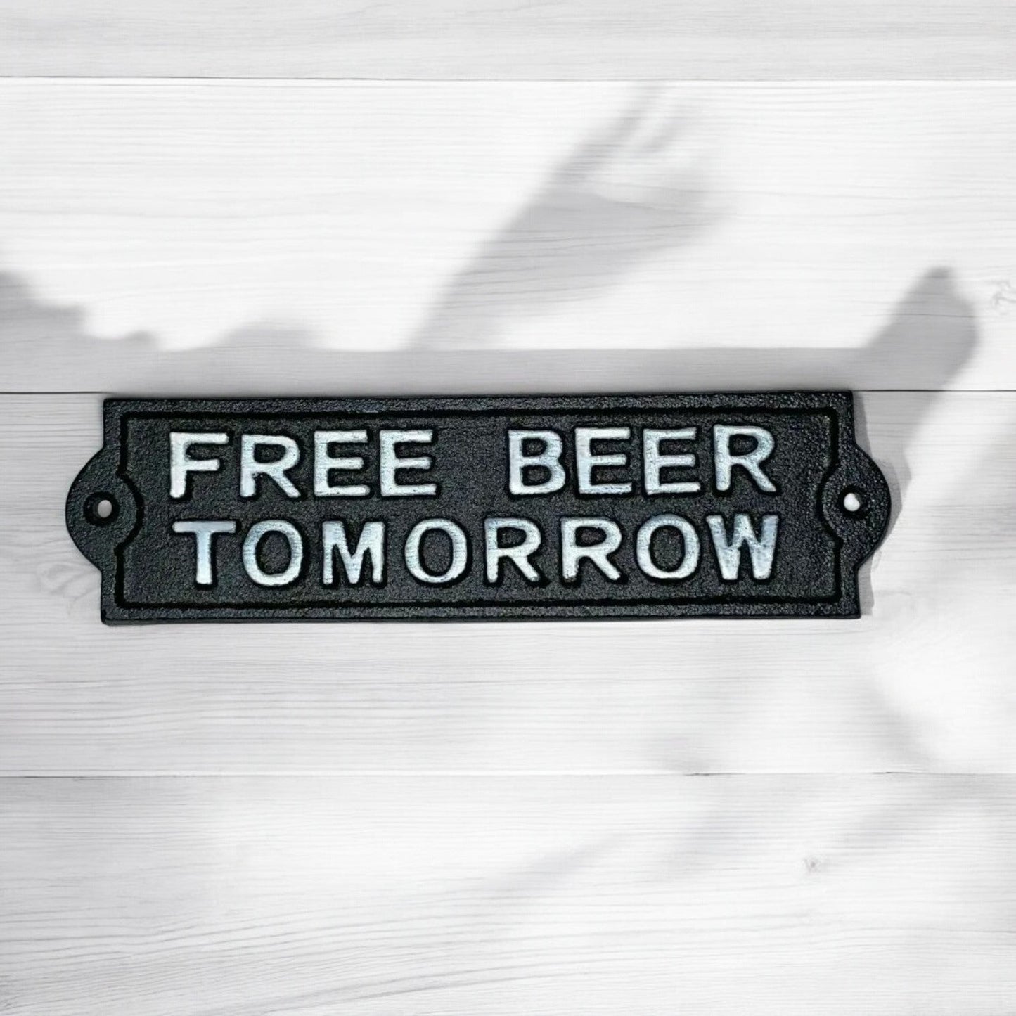 Black metal sign with 'FREE BEER TOMORROW' text on a white background
