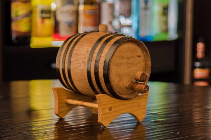 Wooden barrel on a stand with blurred bottles in the background