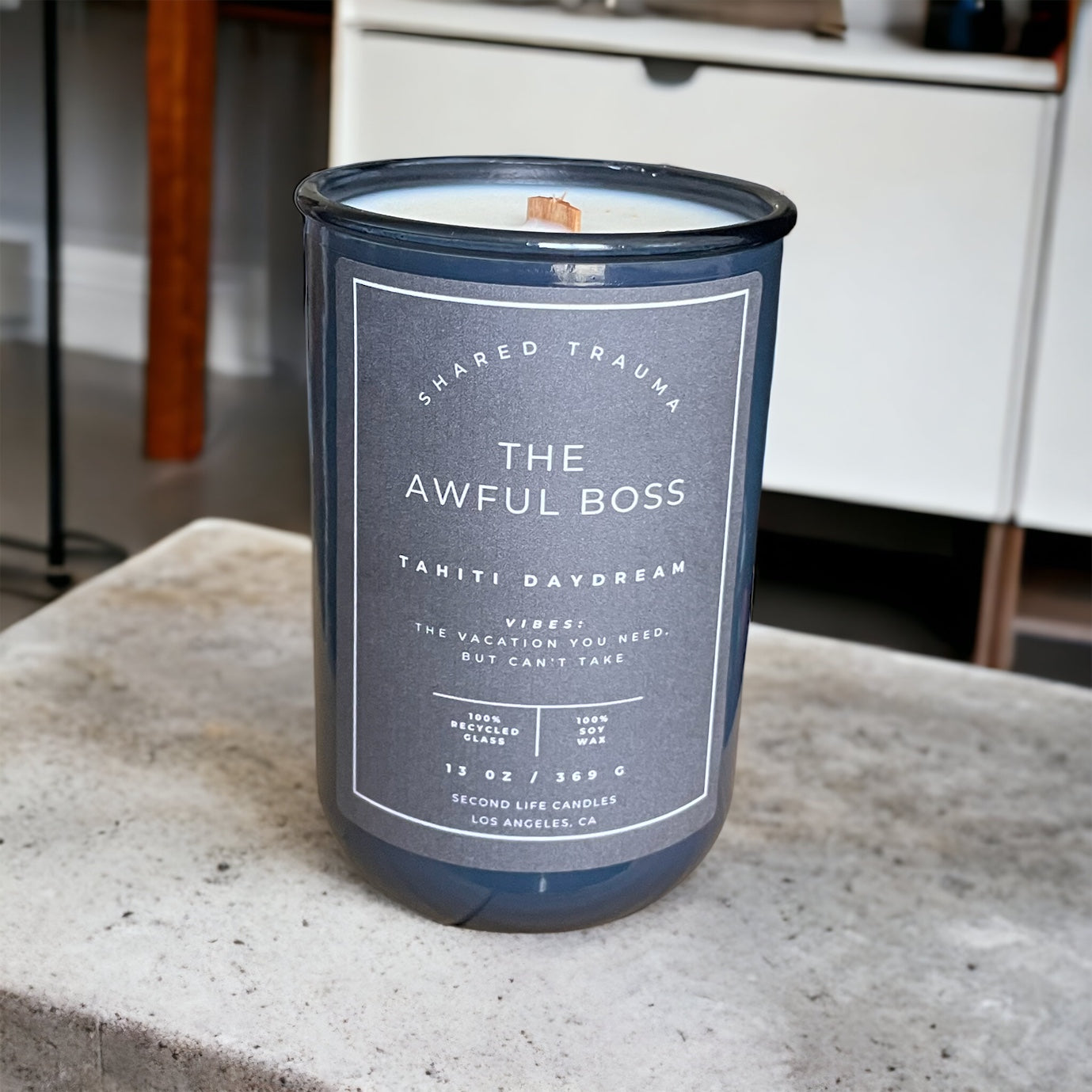 Candle in a blue container with a label on a concrete surface