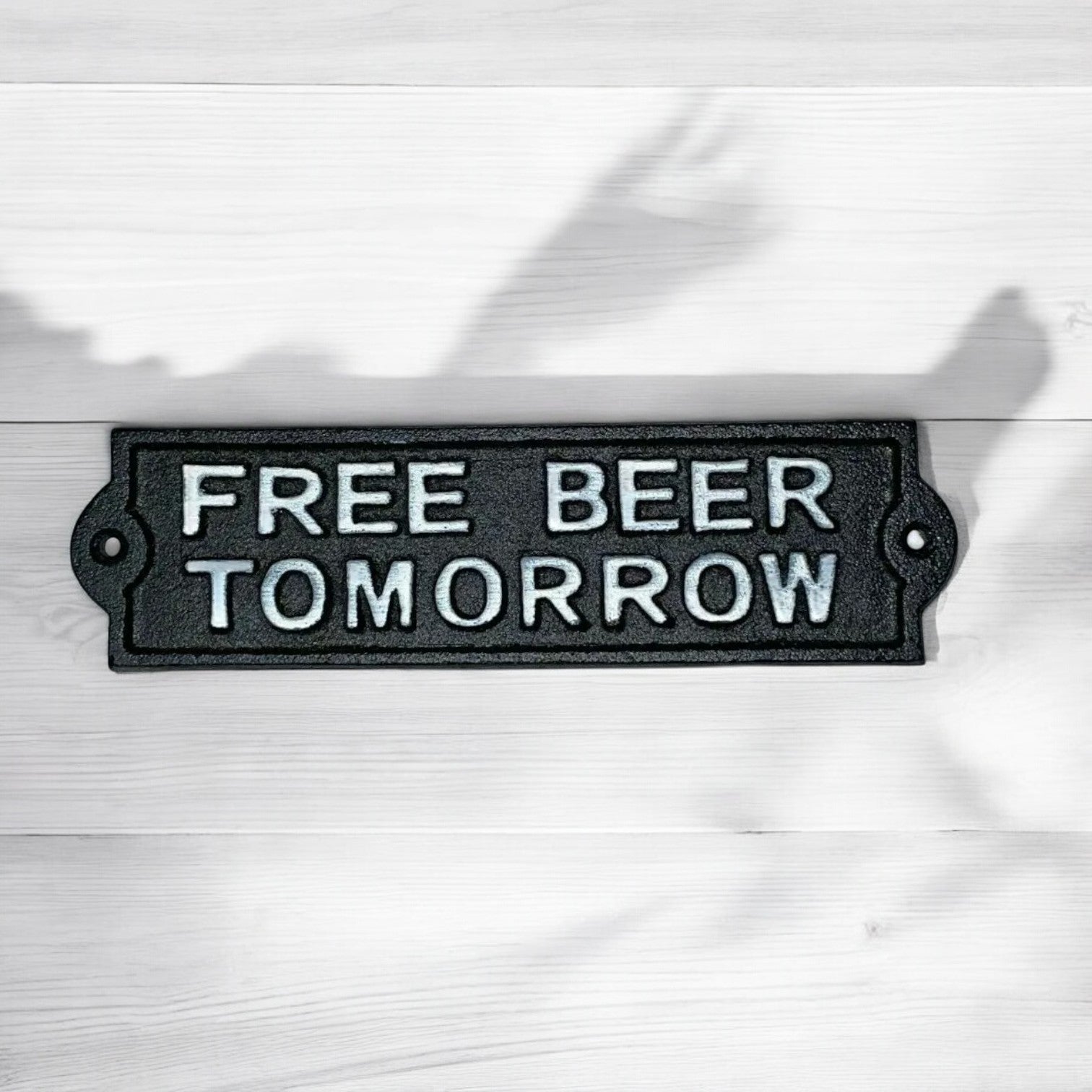 Black metal sign with 'FREE BEER TOMORROW' text on a white background