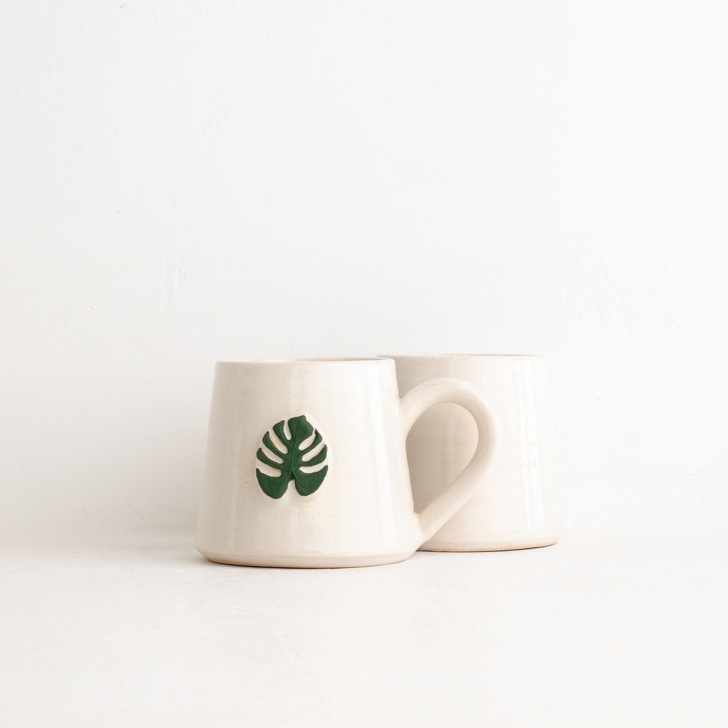 White mug with a green leaf design on a white background
