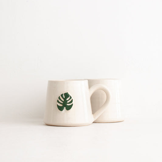 White mug with a green leaf design on a white background